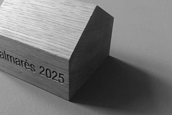 Maison en bois sur laquelle est écrit "Palmarès 2025". Photo en noir et blanc